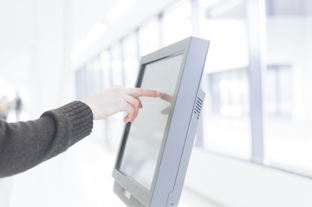 cropped hand of business person touching computer monitor in office