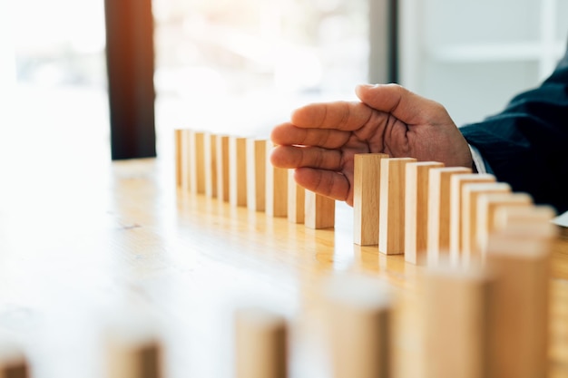 cropped hand of businessman playing with wooden dominoes on table