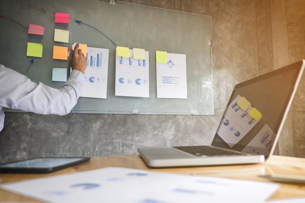 Cropped hand of businessman writing on adhesive note in office