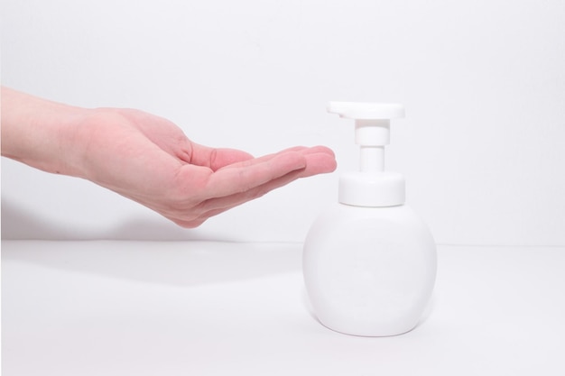 Cropped hand by sanitizer against white background