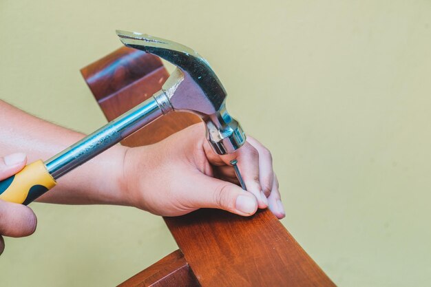 Photo cropped hand of carpenter fixing nail on wood