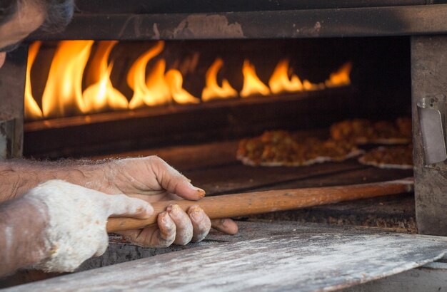 Foto la mano tagliata dello chef che mette la pizza nel forno