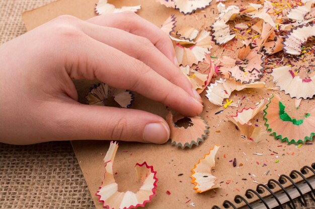 Foto mano tagliata di un bambino che tiene frammenti di matita colorata su un taccuino