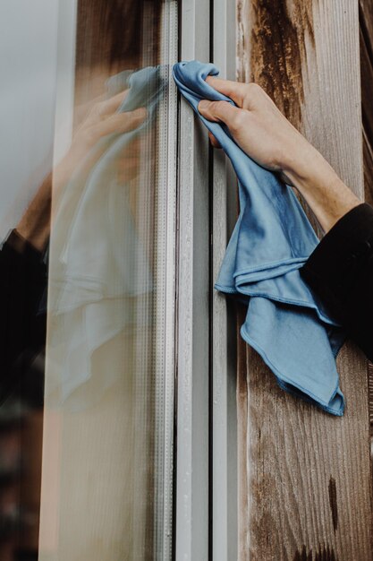 Photo cropped hand of cleaner cleaning glass window