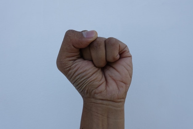 Photo cropped hand clenching fist against blue sky