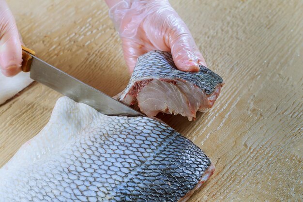 Photo cropped hand cutting fish on table