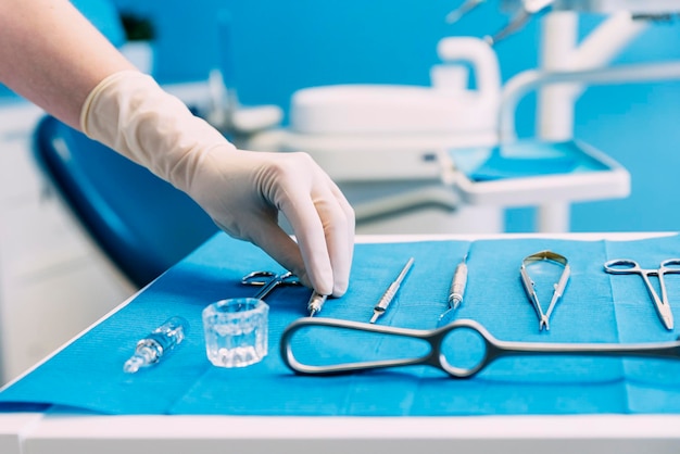 cropped hand of dentist picking dental equipment in clinic
