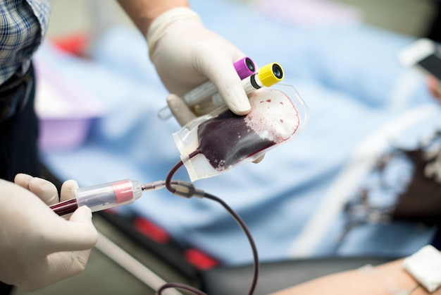 Foto mano tagliata di un medico che inietta in una borsa di sangue