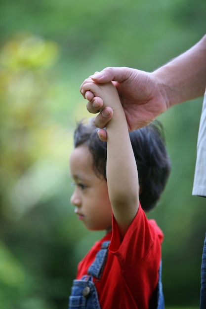 Foto la mano tagliata di un padre che tiene il figlio nel cortile sul retro
