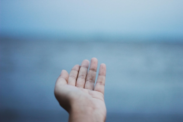 Foto mano tagliata che fa un gesto contro il cielo