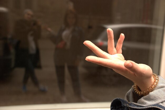 Photo cropped hand gesturing against window