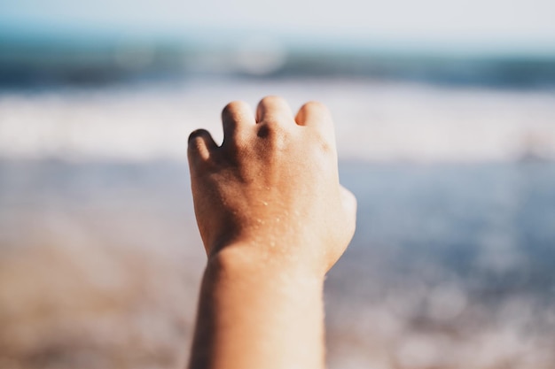 Cropped hand gesturing at beach