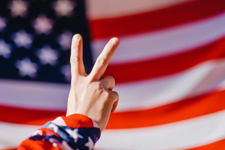 Photo アメリカ国旗に対して平和のサインを示す手を切り取った