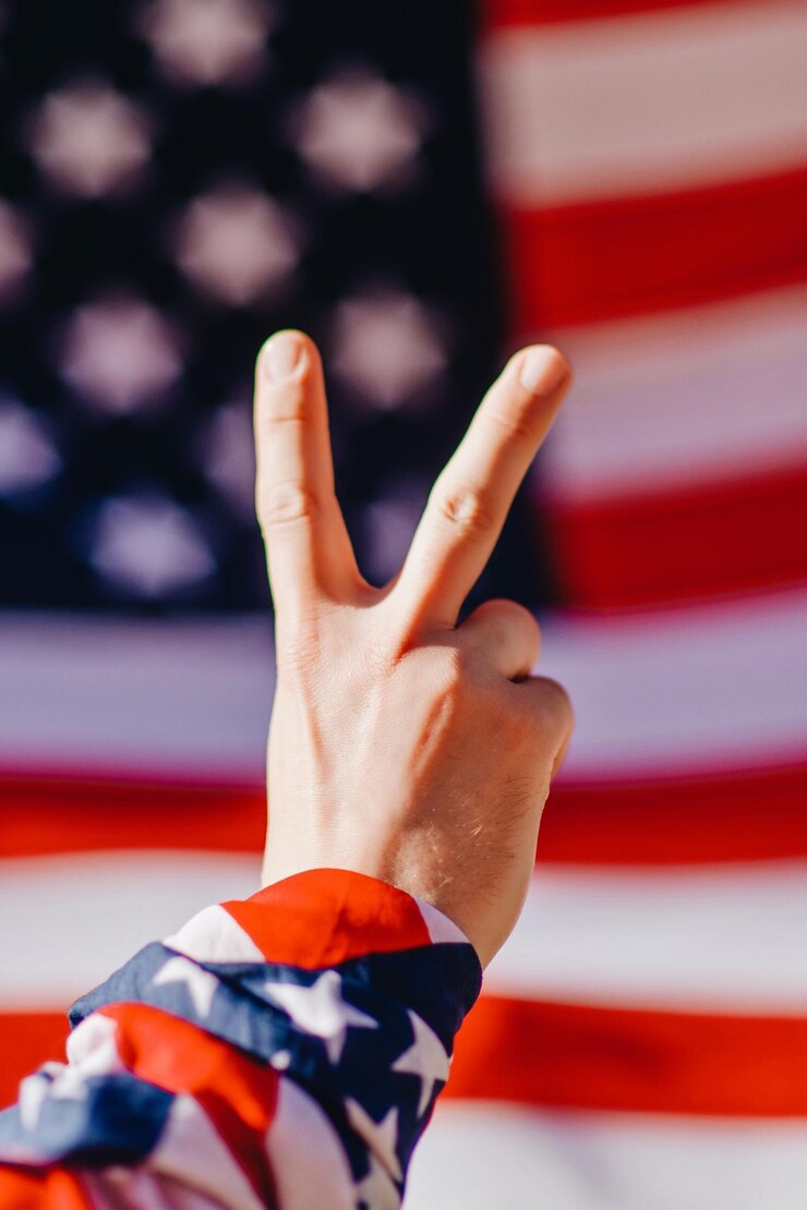 Photo アメリカ国旗に対して平和のサインを示す手を切り取った