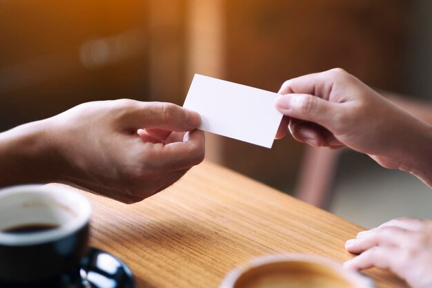 Foto mano tagliata che dà un cartello vuoto a un amico al tavolo in un caffè