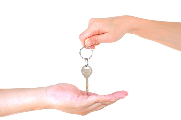 Cropped hand giving key to person against white background