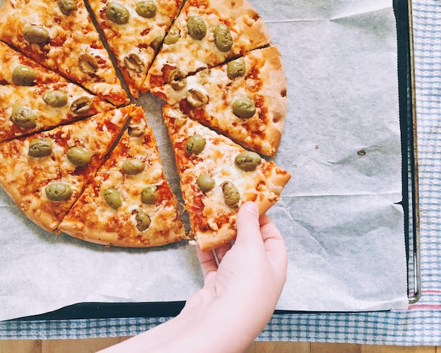 Foto mano tagliata che mangia la pizza