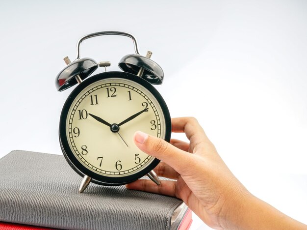 Photo cropped hand holding alarm clock against white background