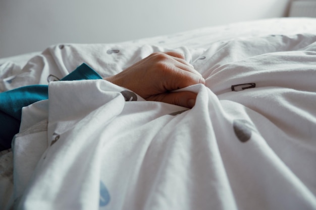 cropped hand holding bed sheet at home