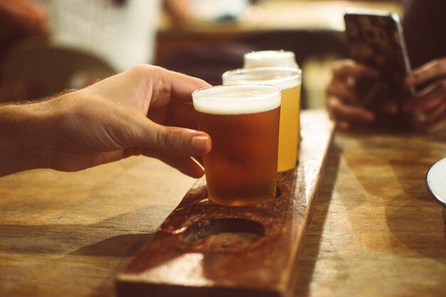 Photo cropped hand holding beer glass on table