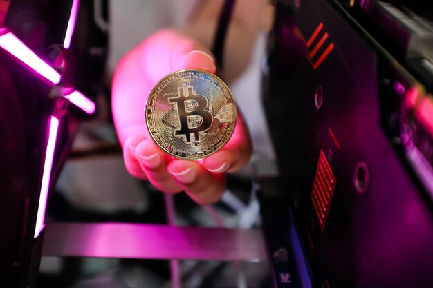 Photo cropped hand holding bitcoin against machine