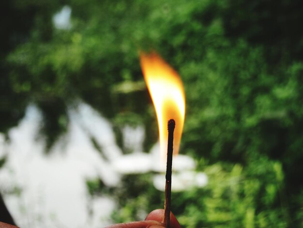 Foto una mano tagliata che tiene un fiammifero in fiamme