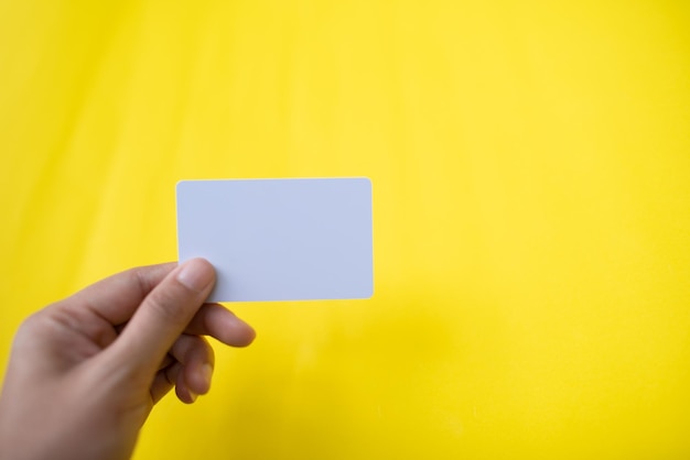 Cropped hand holding business card against yellow background