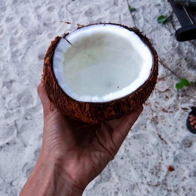 Foto mano tagliata che tiene la noce di cocco