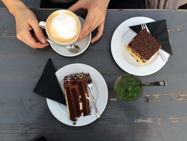 テーブルの上のケーキの横にコーヒーカップを握っている手