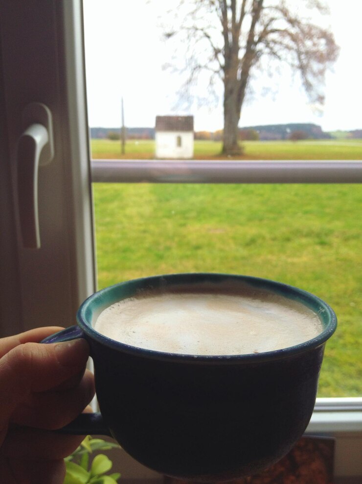Photo cropped hand holding coffee cup by window at home