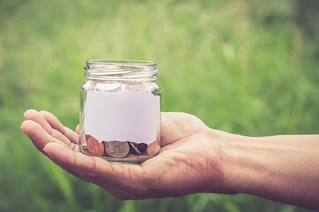 Photo cropped hand holding coin jar