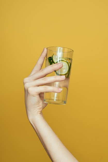 Photo cropped hand holding drink against yellow background