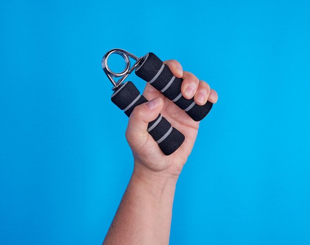 Photo cropped hand holding exercise equipment against blue background