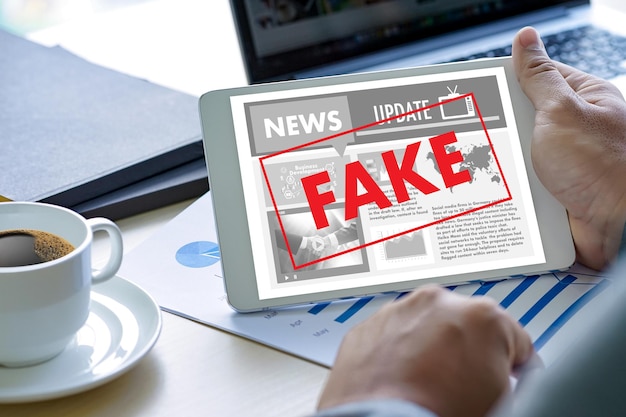 Photo cropped hand holding fake news in digital tablet