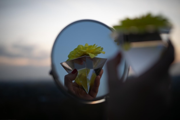 Photo cropped hand holding flower reflecting on mirror