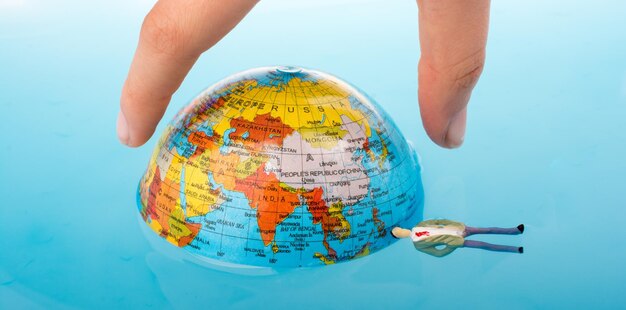 Photo cropped hand holding globe in swimming pool