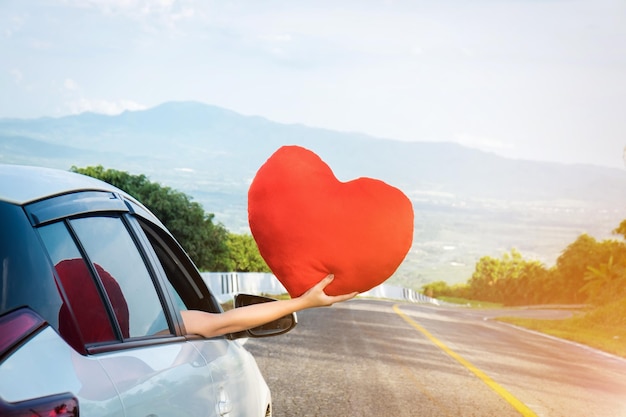 Cropped hand holding heart shape while traveling in car