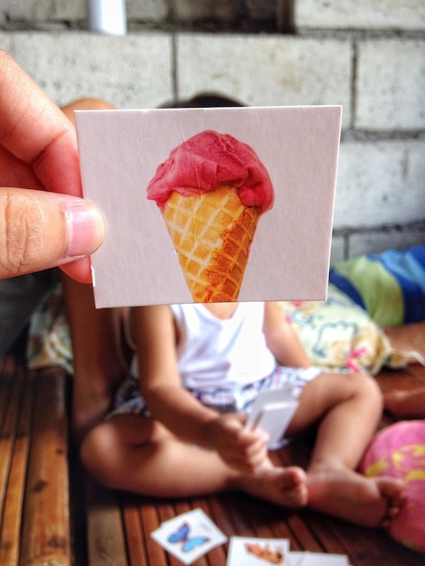 Photo cropped hand holding ice cream photograph against child