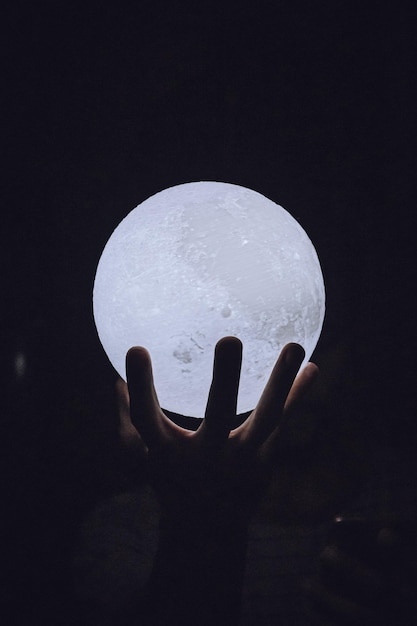 Photo cropped hand holding illuminated crystal ball against black background