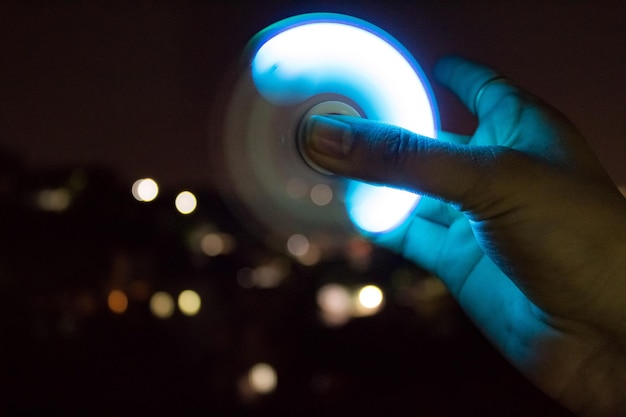 Foto mano tagliata che tiene in mano un giradischi illuminato che gira di notte