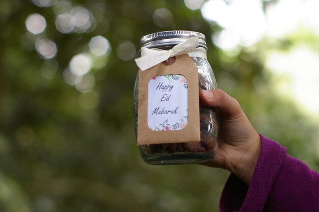 Photo cropped hand holding jar with text during eid