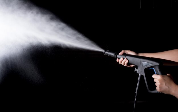 Foto mano tagliata che tiene lo spray a getto contro uno sfondo nero