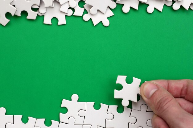 Photo cropped hand holding jigsaw piece over puzzle