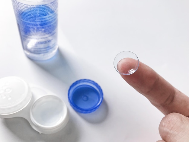 cropped hand holding lens over white background