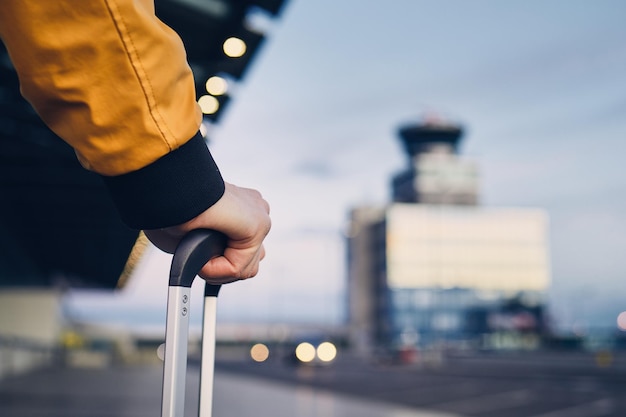 Photo cropped hand holding luggage handle in city