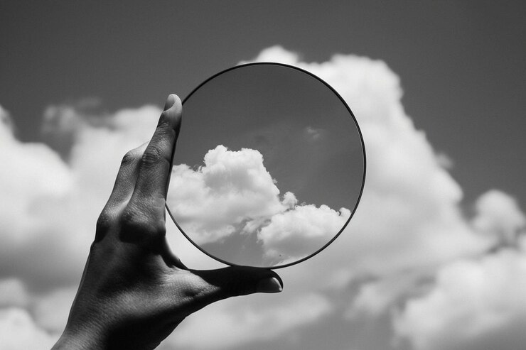 Photo cropped hand holding mirror with sky reflection in darkroom