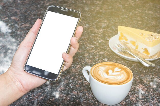 カフェのテーブルでカプチーノで携帯電話を握っている切断された手