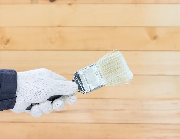 Cropped hand holding paintbrush on table