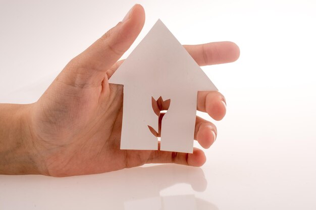 Photo cropped hand holding paper model house over white background