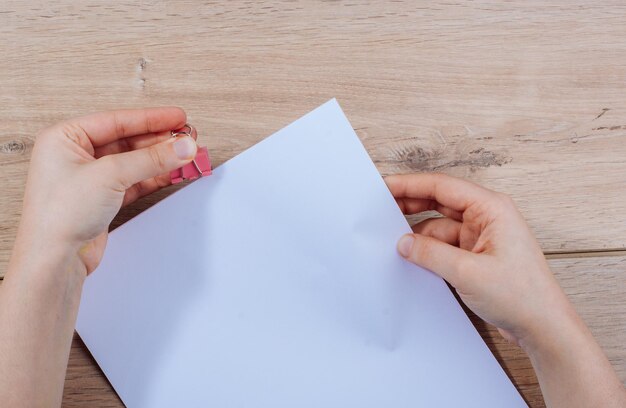 Foto mani tagliate che tengono la carta con la pinza su un tavolo di legno